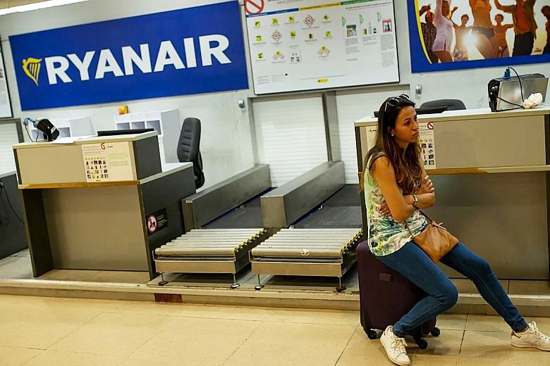 Utas ül a bőröndjén a Ryanair check-in pult előtt egy repülőtéren